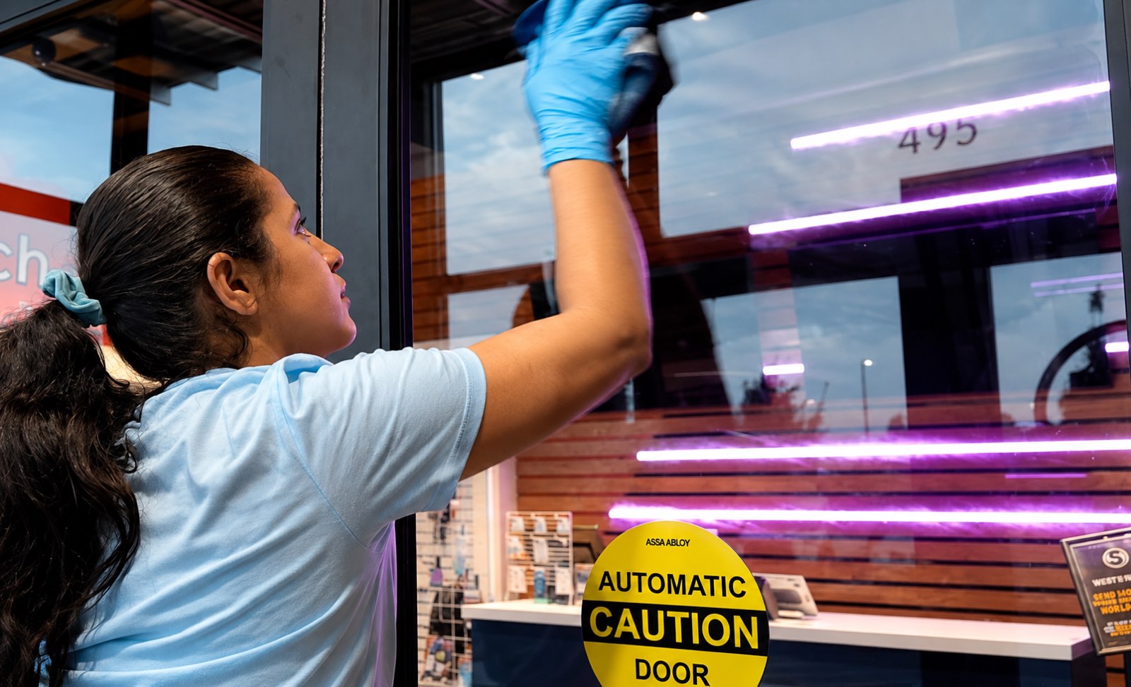 AQS team member cleaning a storefront glass entry door