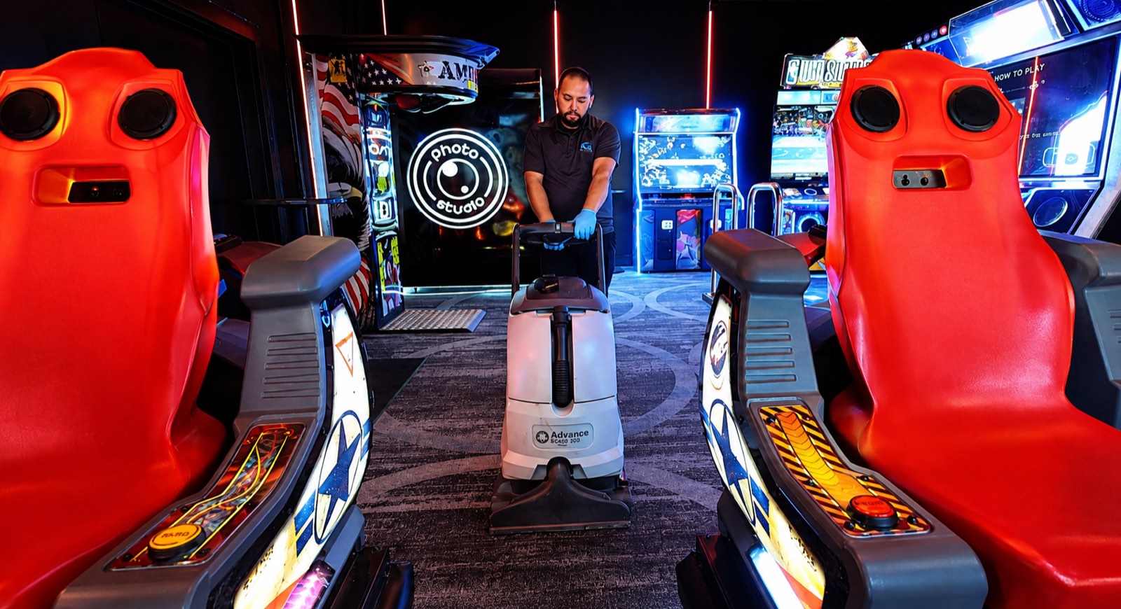 AQS team member cleaning the arcade floor between game cabinets